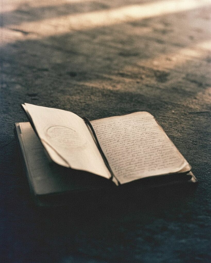 ধুলোমাখা মেঝেতে পুরনো খোলা ডায়েরি ও ভোরের আলো — স্মৃতির ভার ও মুক্তির প্রতীক