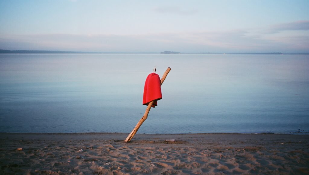 be your authentic self — a child’s towel-cape pinned to driftwood by a quiet lakeshore