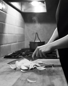 A person engaged in depression cooking at 2 AM, slicing onions to cope with loneliness and emotional numbness.