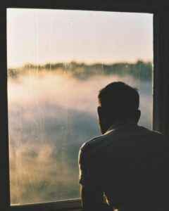 A lonely silhouette by a misty window, feeling homesick for nowhere that exists on any map