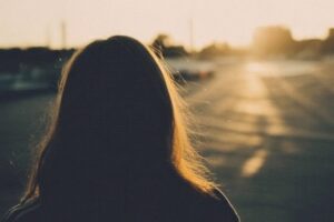Person looking back at sunset with contemplative expression, symbolizing false nostalgia and selective memory