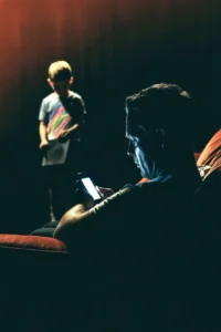 Father looking at phone while son waits with a drawing.